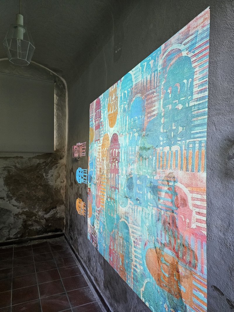 Buntes Kunstwerk an einer Betonwand in einem Raum. Kunstinstallation mit farbenfrohen Mustern.