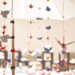 Origami-Dekoration auf der Kulturnacht in Radolfzell. Papierkraniche, Elefanten und Boote hängen an Fäden.