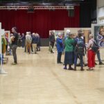 Kulturnacht Radolfzell: Besucher betrachten Kunstausstellung in Halle, rote Vorhänge im Hintergrund.