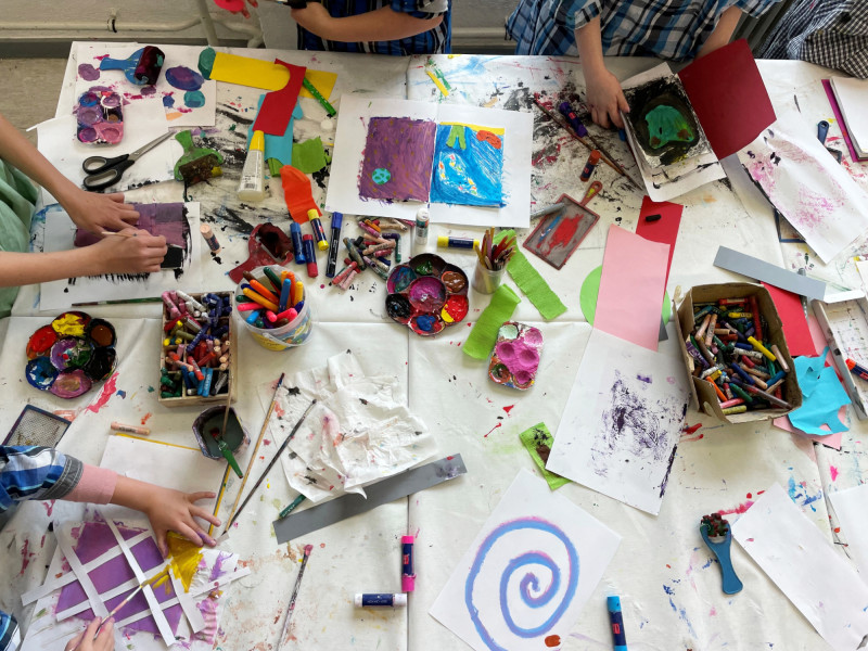 Kinder basteln und malen mit Farbe, Stiften und Papier an einem Tisch. Kreatives Kunstprojekt für Kinder.