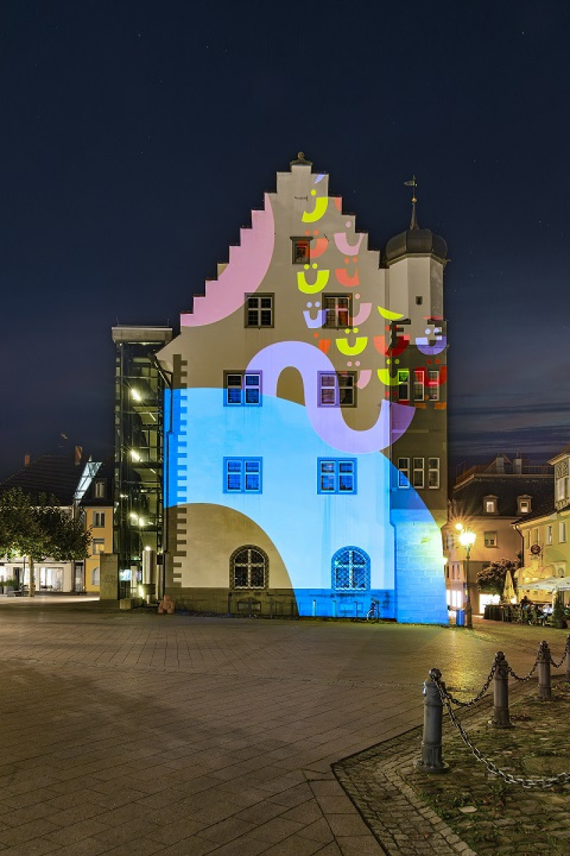 Illuminiertes Rathaus in Ravensburg bei Nacht. Farbenfrohe Lichtkunst am Gebäude. Stadtansicht mit besonderer Beleuchtung.