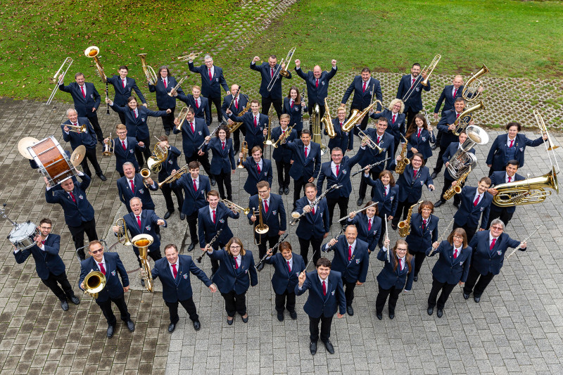 Großes Blasorchester in Uniform, Gruppenfoto im Freien. Musikverein mit Instrumenten wie Trompete, Posaune, Saxophon.