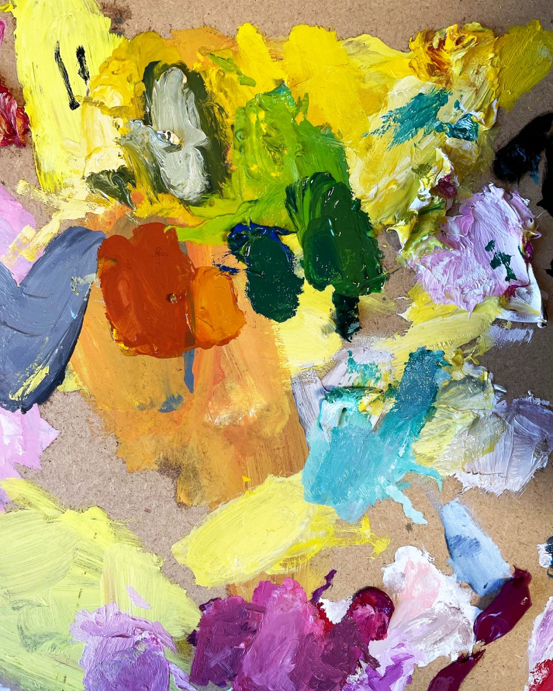 Farbpalette mit lebhaften Ölfarben in Gelb, Grün, Orange, Blau und Lila. Künstlerische Textur und Farbmischung.