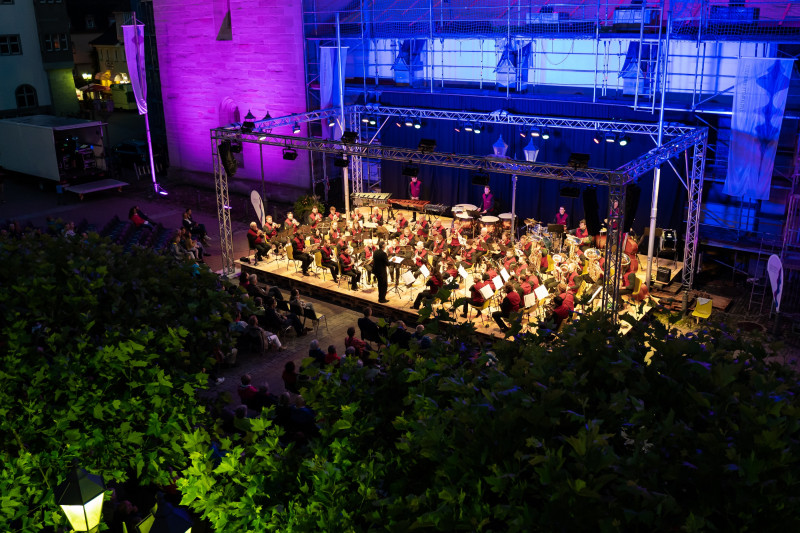 Konzertabend: Orchester spielt auf der Bühne vor Publikum. Musikveranstaltung im Freien.